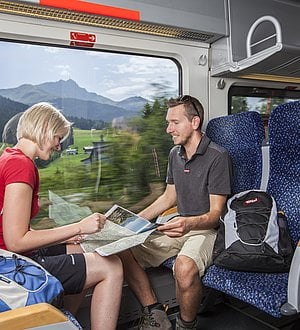 Wanderer sitzen sich im Zug gegenüber 